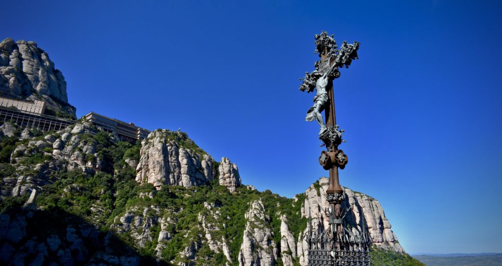 Creu de Puig i Cadafalch amb monestir al fons